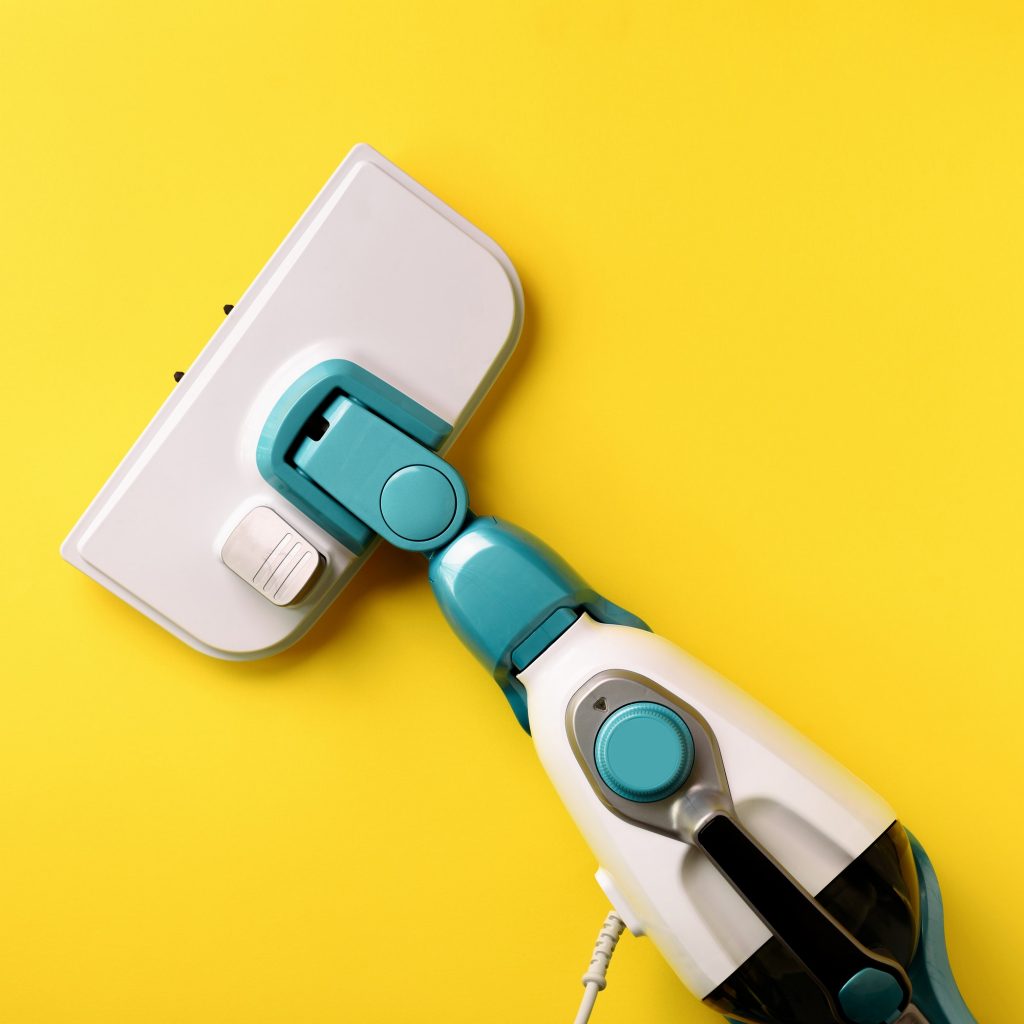 Steam cleaner mop on yellow background. Top view, flat lay. Banner with copy space. Cleaning service